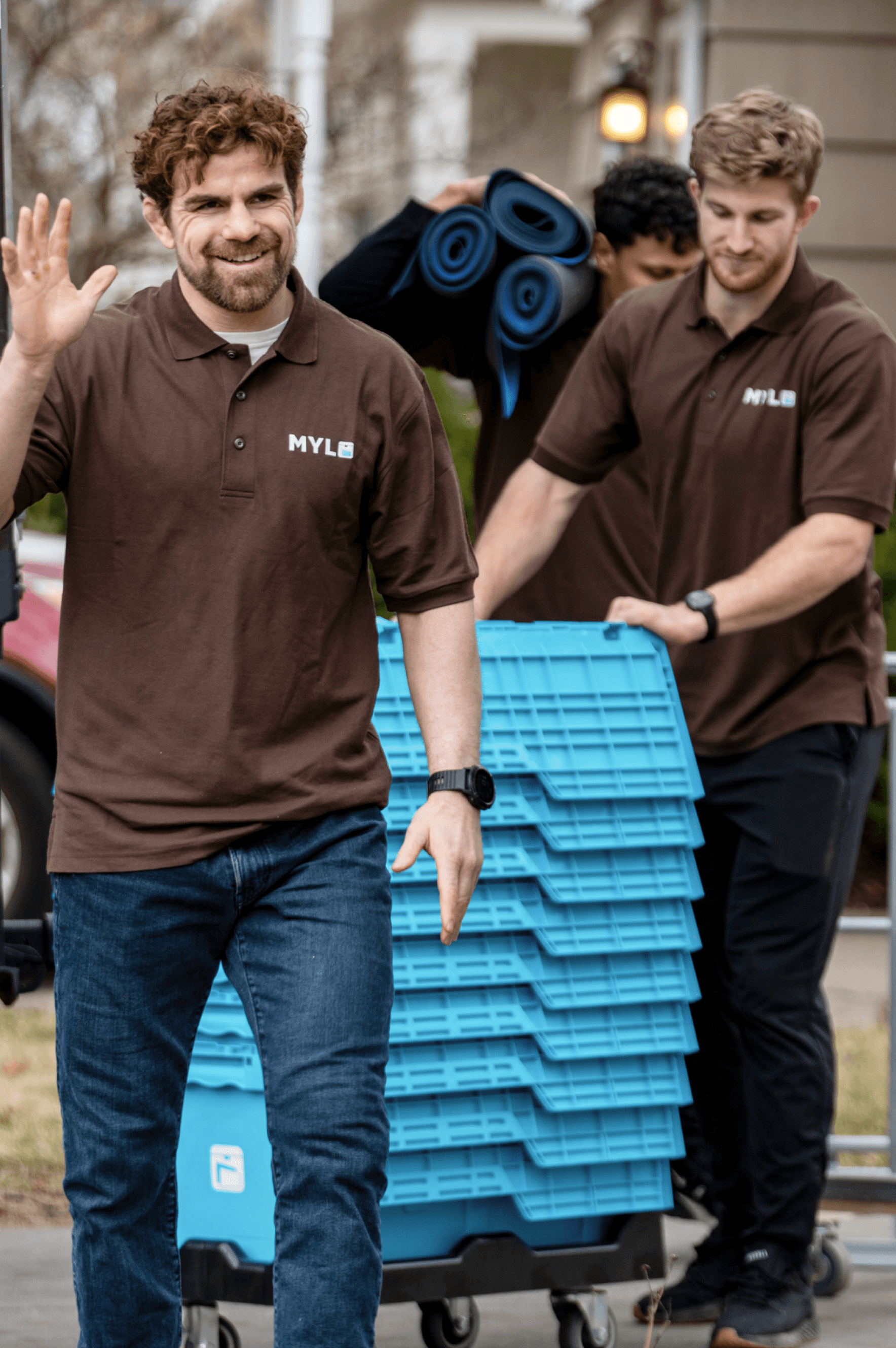 Two MYLO movers wheeling stacked storage totes up a driveway